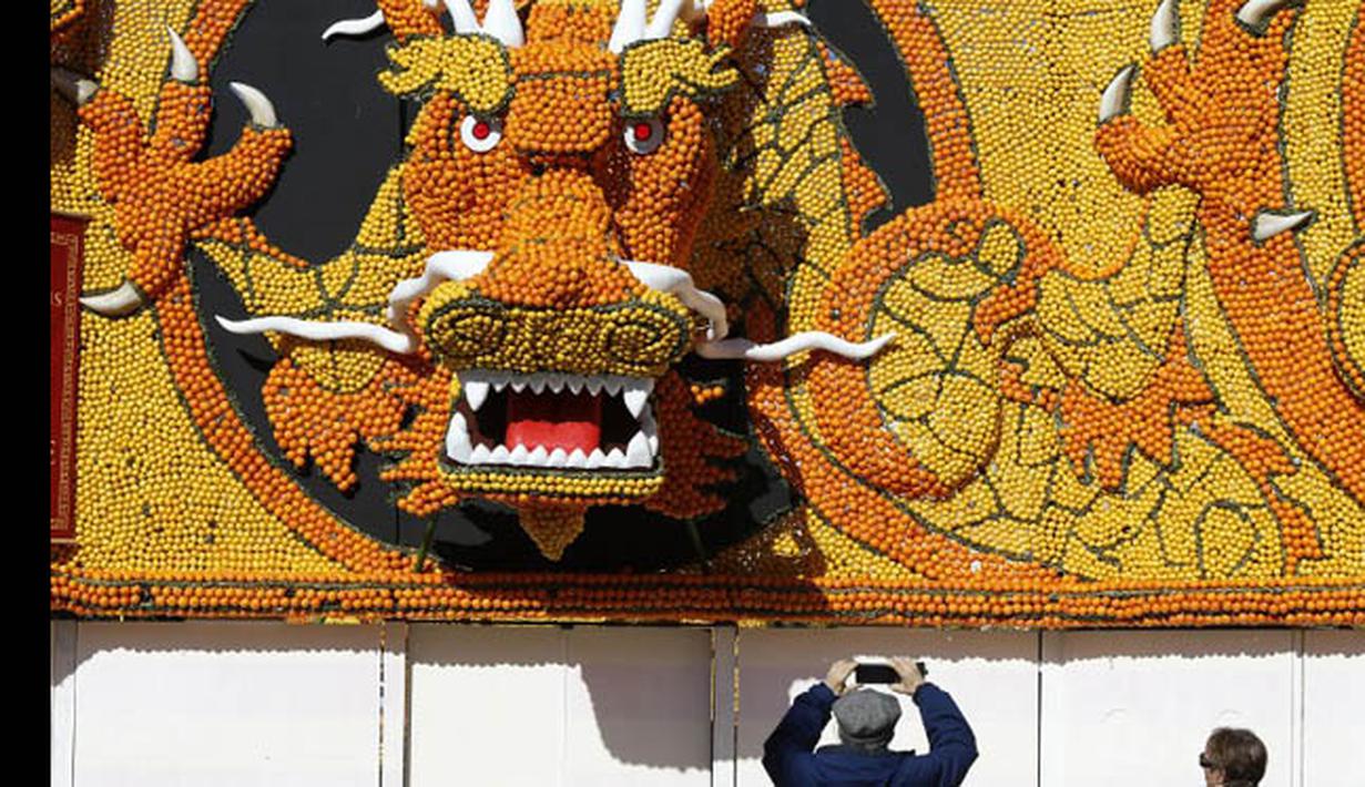 Pengunjung mengambil gambar patung yang terbuat dari jeruk dan lemon di Menton, sebuah kota kecil di Perancis, Rabu (12/2/2015). (AFP PHOTO/Valery Hache)