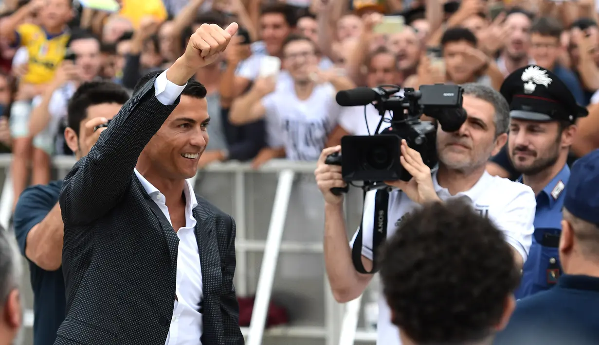 Cristiano Ronaldo menyapa suporter Juventus saat tiba di pusat layanan kesehatan Juventus (J-Medical), Turin, Italia, (16/7). Ronaldo akan mengenakan nomor punggung 7, seperti yang dikenakannya di Real Madrid. (AFP Photo/Miguel Medina)