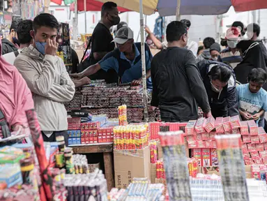 Sejumlah pedagang menjajakan kembang api dagangannya di Pasar Asemka, Jakarta, Selasa (28/12/2021). Menjelang perayaan Tahun Baru, para pedagang musiman menjual petasan dan kembang api di bahu jalan serta kolong jembatan kawasan Pasar Pagi Asemka. (Liputan6.com/Faizal Fanani)