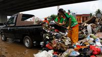 Petugas PPSU DKI Jakarta menaikkan sampah sisa banjir ke atas mobil di bawah Tol Becakayu, Cipinang Melayu, Jakarta Timur, Rabu (8/1/2020). Sampah sisa banjir tersebut selanjutnya diangkut ke TPA Bantar Gebang. (merdeka.com/Magang/Muhammad Fayyadh)