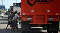 Sejumlah warga mencoba mencuri beras dari truk kargo yang tiba di pelabuhan di Puerto Cabello, Venezuela, Selasa (23/1). Penjarahan sporadis, kerusuhan pangan dan protes yang didorong oleh kelaparan telah melonjak di Venezuela. (AP Photo/Fernando Llano)