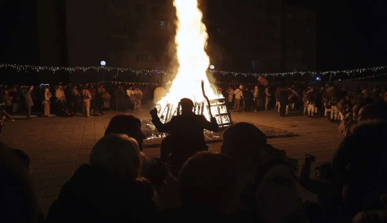 Para penari melakukan ritual kuno di sekitar api unggun mengusir roh-roh jahat di jalan-jalan Batanovci, Bulgaria, Kamis (13/1/2022). Untuk dua tahun ini festival topeng memiliki arti ekstra: orang-orang berharap itu akan membawa kelegaan dari kesengsaraan pandemi corona. (AP/Valentina Petrova)