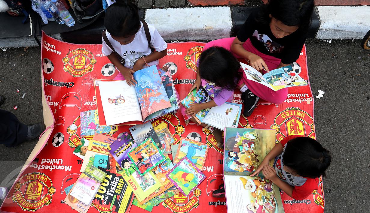Sejumlah anak membaca buku di Kawasan Bundaran HI saat berlangsungnya Hari Bebas Kendaraan Bermotor atau Car Free Day (CFD), Jakarta, Minggu (2/4). Gerakan yang digagas oleh komunitas "Buku 100 Desa" . (Liputan6.com/Johan Tallo)