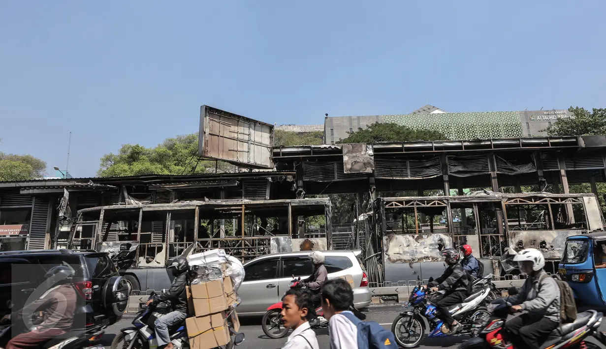 Pengendara melintas di dekat Bus Transjakarta yang terbakar di Halte UI Salemba, Jakarta, Jumat (3/7). Akibat kebakaran tersebut, Halte UI Salemba rusak ringan. (Liputan6.com/Faizal Fanani) 
