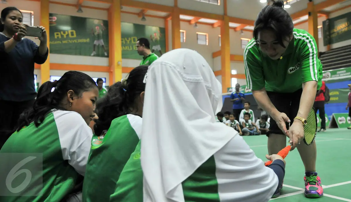 Legenda Bulutangkis Indonesia, Susi Susanti memberi tahu cara memegang raket yang benar kepada peserta MILO School Competition 2015, Jakarta, Sabtu (28/11/2015). (Liputan6.com/Yoppy Renato)