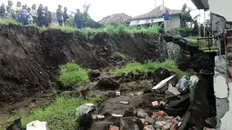 Warga melihat sebuah rumah yang rusak parah akibat tertimpa tanah longsor di Kecamatan Kintamani, Bali, Jumat (10/2). Sebanyak 12 orang dilaporkan meninggal akibat musibah yang terjadi di tiga desa di Kecamatan Kintamani (STR/NATIONAL DISASTER AGENCY/AFP)