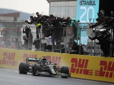 Pembalap Mercedes dari Inggris Lewis Hamilton disambut para kru setelah melewati garis finis F1 GP Turki di sirkuit balap Istanbul Park di Istanbul, Minggu (15/11/2020). Pebalap Formula 1 Lewis Hamilton resmi meraih juara dunia Formula 1 2020. (Tolga Bozoglu/Pool via AP)