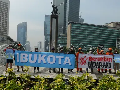 Aktivis dari Gerakan Inisiatif Bersihkan Udara Koalisi Semesta (Ibu Kota)membentangkan spanduk saat melakukan kampanye damai terkait buruknya udara Jakarta di Bundaran HI, Jakarta, Rabu (5/12). (Merdeka.com/Imam Buhori)