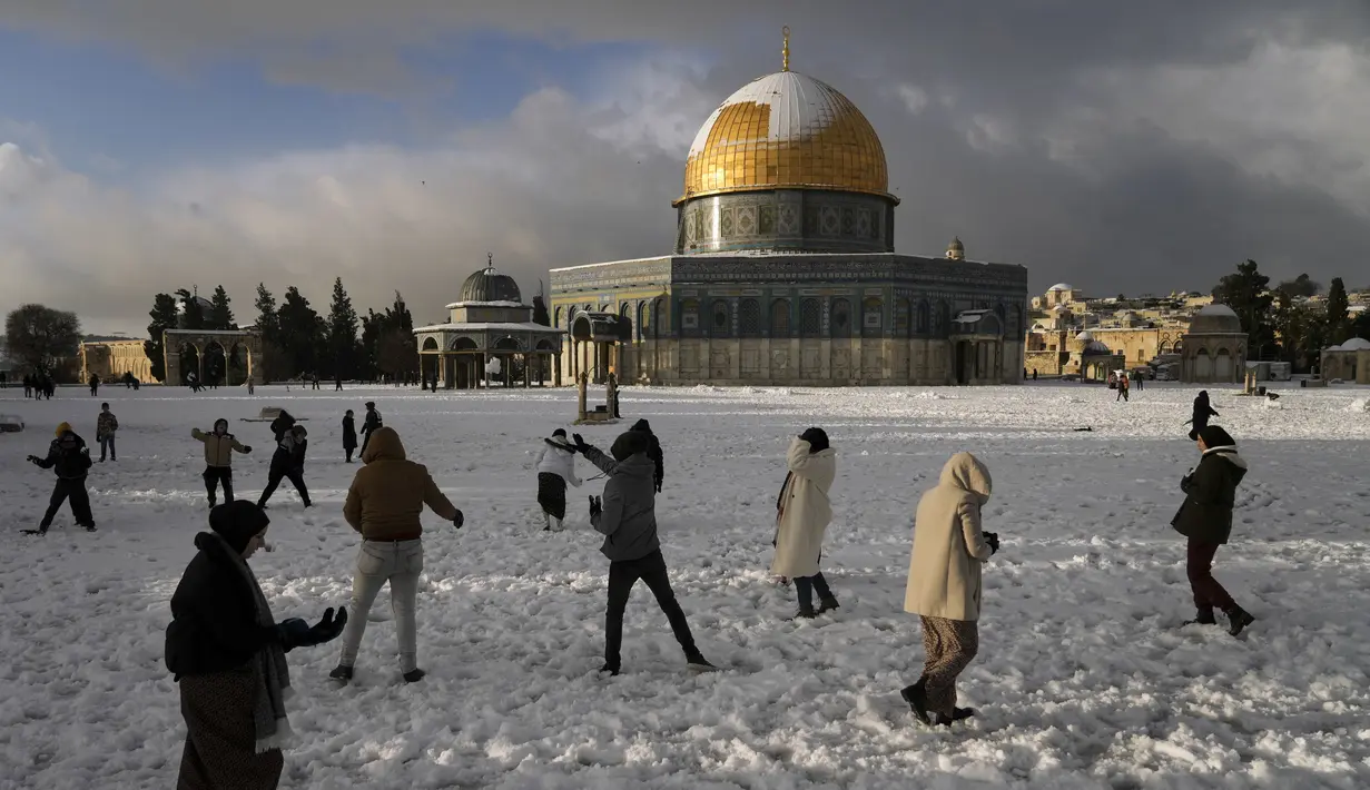 Warga Palestina menikmati salju di sebelah Masjid Kubah Batu di kompleks Masjid Al Aqsa di Kota Tua Yerusalem, Kamis (27/1/2022). Hujan salju yang jarang melanda sebagian wilayah Israel dan Tepi Barat, menutup sekolah dan bisnis. (AP Photo/Mahmoud Illean)
