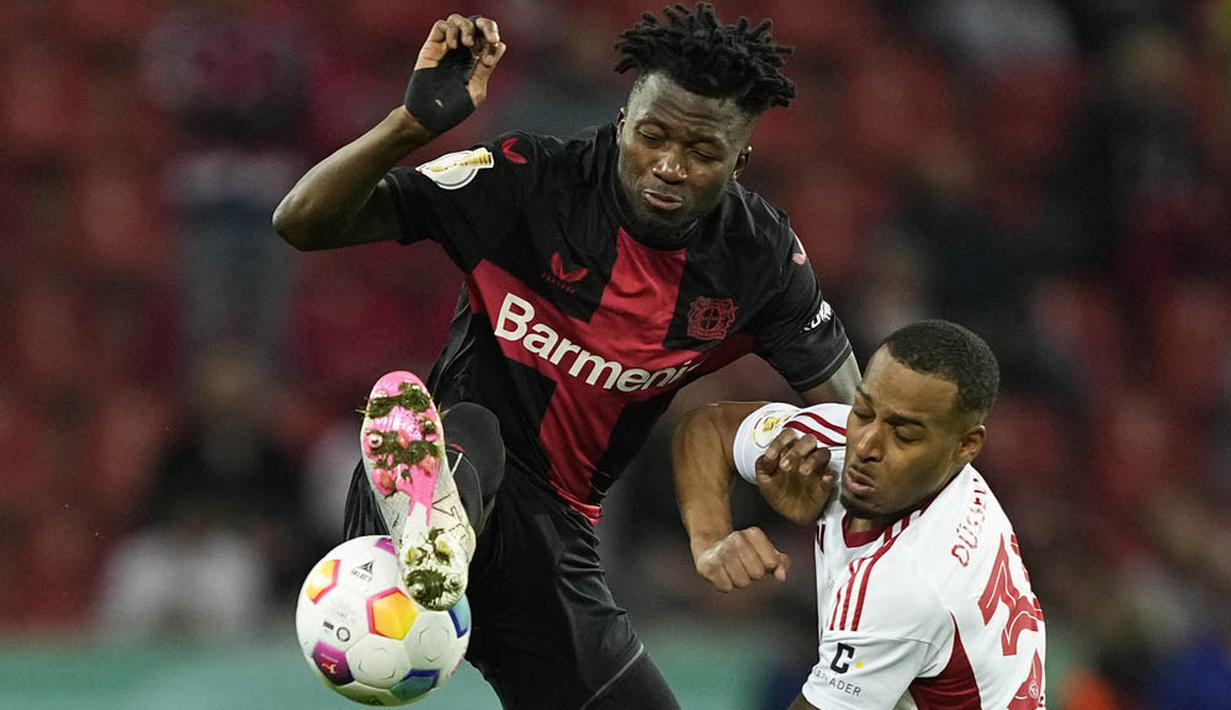 Pemain Bayer Leverkusen, Edmond Tapsoba, berebut bola dengan pemain Fortuna Duesseldorf, Suliman Marlon Mustapha, pada laga semifinal DFB Pokal di Stadion BayArena, Kamis (4/4/2024). (AP Photo/Martin Meissner)