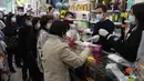Warga menerima masker wajah gratis dalam sebuah toko kosmetik di Tsuen Wan, Hong Kong, Selasa (28/1/2020). Hong Kong terkonfirmasi memiliki delapan kasus infeksi virus corona. (AP Photo/Achmad Ibrahim)