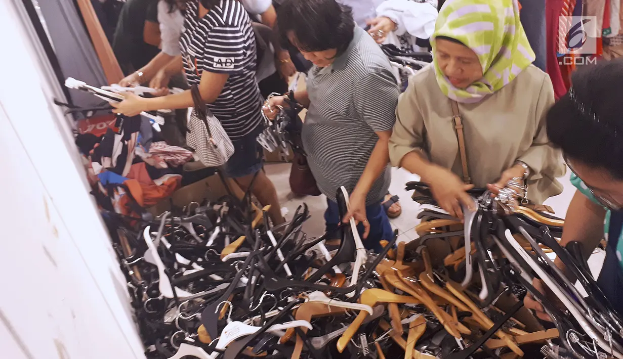 Pembeli berebut sisa gantungan baju atau hanger saat midnight sale di gerai Debenhams, Senayan City, Jakarta, Sabtu (30/12). PT Mitra Adiperkasa Tbk (MAP) menutup gerai Debenhams dengan diskon besar-besaran di akhir tahun 2017. (Liputan6.com/Fery Pradolo)