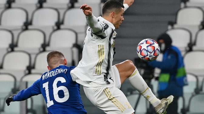 Bek Dynamo Kiev, Vitaliy Mikolenko (kiri) dan penyerang Juventus, Cristiano Ronaldo melompat saat berebut bola pada matchday kelima Grup G Liga Champions di Allianz Stadium, Kamis (3/12/2020) dinihari WIB. Juventus meraih kemenangan 3-0 atas tamunya Dynamo Kyiv. (Vincenzo PINTO / AFP)