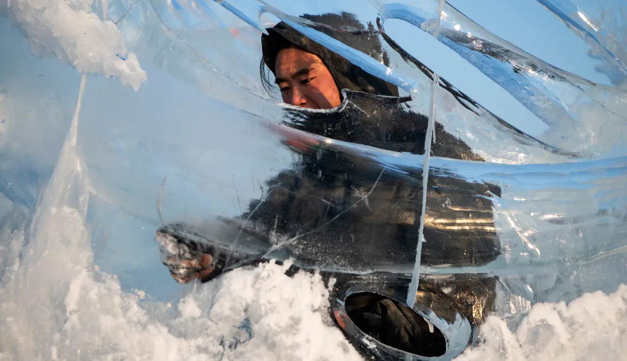 Pemahat es memberikan sentuhan akhir pada patung es di festival Ice and Snow World Harbin, di Harbin, timur laut China, Jumat (3/1/2019). Menjadi acara tahunan, festival es terbesar dunia ini menghadirkan beragam patung es dengan bentuk yang besar dan mewah bagi para pengunjungnya. (NOEL CELIS/AFP)