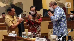 Menteri Dalam Negeri Tito Karnavian (kiri) menyapa Ketua KPU Hasyim Asy’ari (kanan) saat rapat kerja dengan Komisi II DPR RI di Kompleks Parlemen, Senayan, Jakarta, Selasa (7/6/2022). Rapat membahas Peraturan KPU (PKPU) tentang Tahapan dan Jadwal Pemilu 2024. (Liputa6.com/Angga Yuniar)