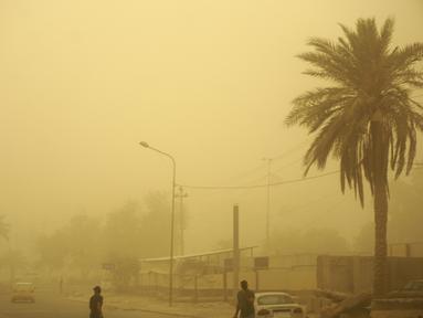 Orang-orang berjalan di jalan di ibu kota Irak, Baghdad, saat debu tebal akibat badai pasir menyelimuti kota itu, pada Senin (23/5/2022). Irak menutup bandara dan gedung-gedung publik saat badai pasir -- yang kesembilan sejak pertengahan April -- melanda negara itu, kata pihak berwenang. (Sabah ARAR / AFP)