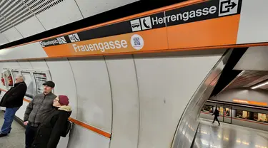 Para pelancong menunggu kereta bawah tanah U3 mereka di stasiun Herrengasse (Jalan Pria) yang ditutup dengan tanda sementara Frauengasse (Jalan Wanita) untuk merayakan Hari Perempuan Internasional di Wina, Austria, Rabu (8/3/2023). Dalam bahasa Inggris, ini berarti mengubah nama dari "Men's Lane" menjadi "Women's Lane". (JOE KLAMAR / AFP)