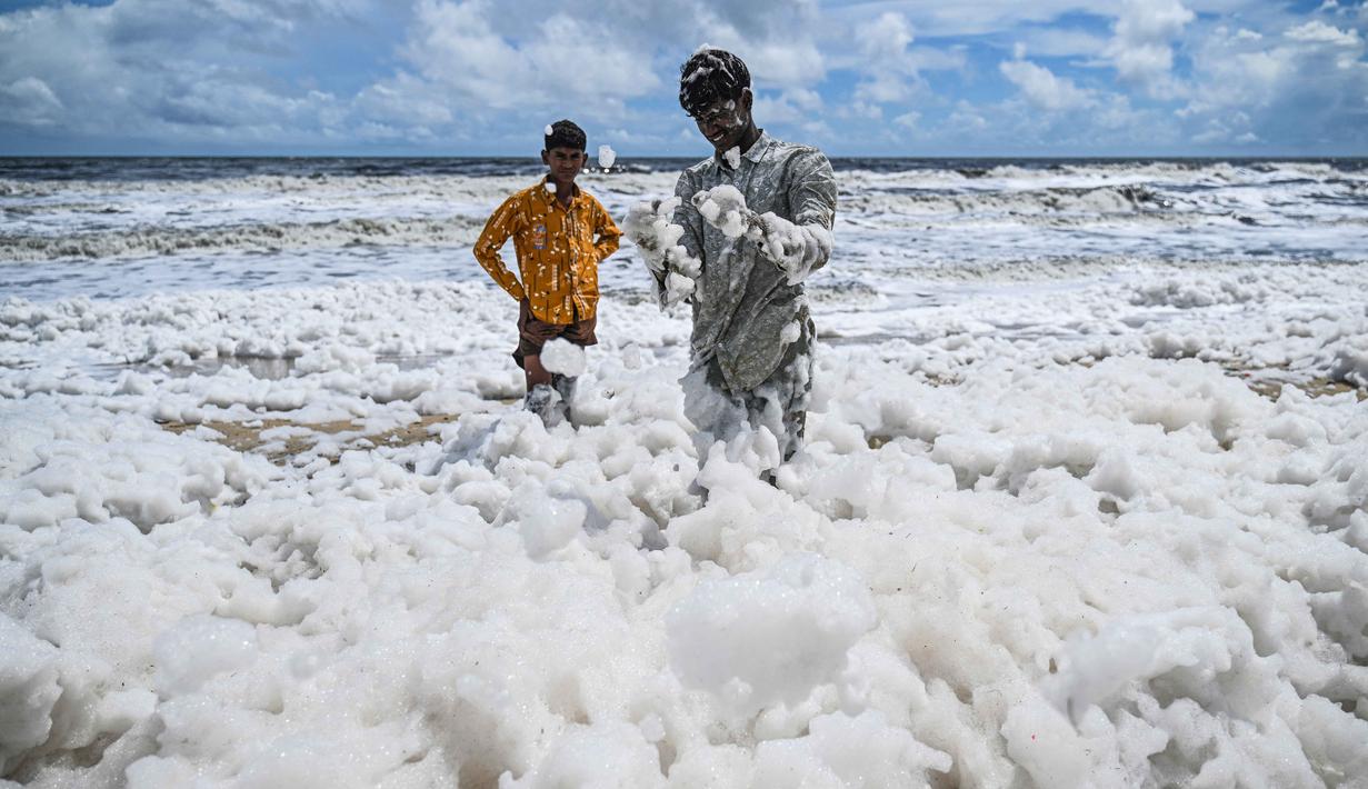Anak-anak bermain di lapisan busa putih tebal yang beracun yang menutupi Pantai Marina yang tercemar di Chennai pada 22 Oktober 2025. (R. Satish BABU/AFP)