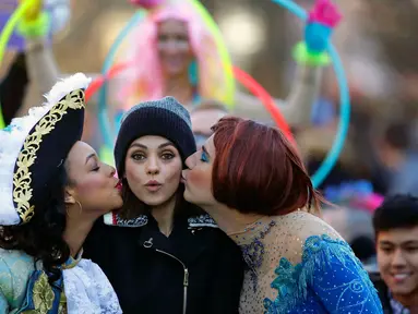 Aktris Mila Kunis (tengah) dicium oleh Amira Weeks (kiri) dan Jacques Berguig dalam sebuah parade di Cambridge (25/1). Mila Kunis dinobatkan sebagai "Woman of the Year" oleh kelompok teater Hasty Pudding. (AP Photo / Charles Krupa)