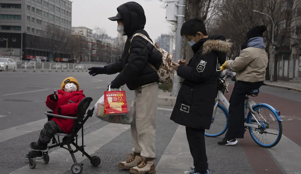 Seorang anak dengan masker melihat ke belakang di jalan Beijing, China, Jumat (2/12/2022). Lebih banyak kota melonggarkan pembatasan, memungkinkan pusat perbelanjaan, supermarket, dan bisnis lainnya dibuka kembali menyusul protes akhir pekan lalu di Shanghai dan daerah lain di mana beberapa orang menyerukan Presiden Xi Jinping untuk mengundurkan diri. (AP Photo/Ng Han Guan)