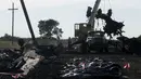 Sebuah alat berat mengangkat puing pesawat MH-17 di belakang deretan jenasah korban yang berhasil ditemukan tim penyelamat di desa Hrabove, Donetsk, Ukraina, (20/7/2014). (REUTERS/Maxim Zmeyev)