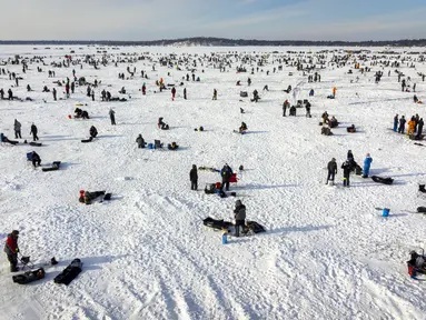 Pemancing di dekat lubang pemancingan saat Brainerd Jaycees Ice Fishing Extravaganza tahunan ke-32 di Gull Lake's Hole di Teluk Day, Minnesota pada 29 Januari 2022. Hampir 10.000 pemancing dari Minnesota dan negara bagian lain menghadiri kontes memancing es amal terbesar di dunia. (Kerem Yucel/AFP)