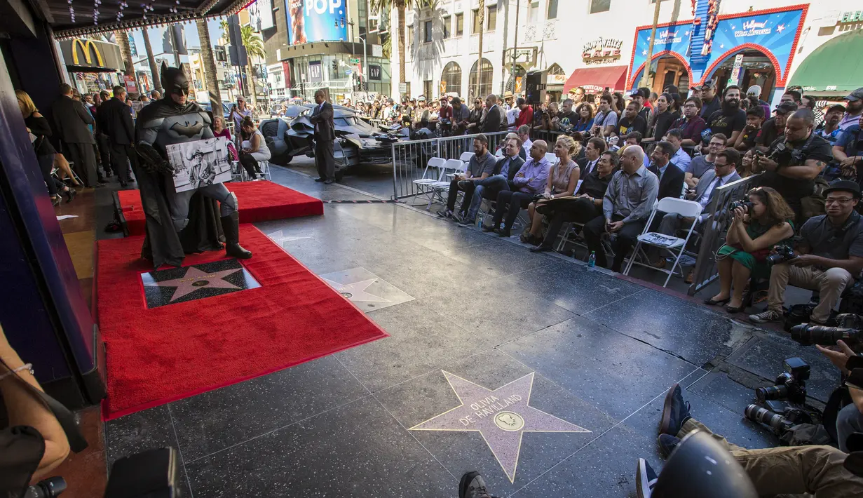 Seorang pria berkostum Batman tampak membawa foto Bob kane sang pembuat karakter Batman di Walk of Fame, Los Angeles, California, Rabu (21/10/2015). Ratusan Warga hadir dalam prosesi ini. (REUTERS/Mario Anzuoni)