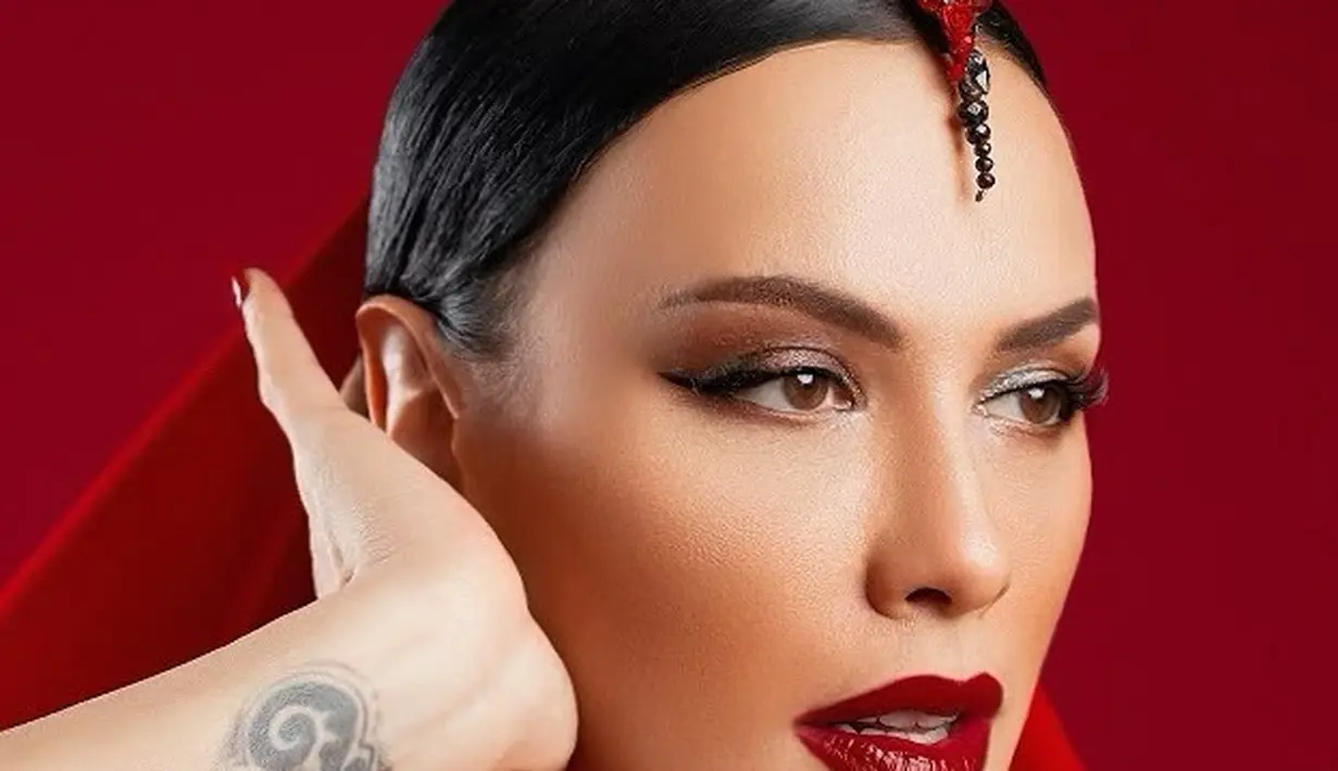 Sophia Latjuba memang selalu mengejutkan dengan penampilannya yang awet muda. Seperti tak pernah muda seharipun, Sophia tampil dengan makeup bold yang menonjolkan area matanya dan bibir merah. Penampilannya ini ditunjang dengan latar photoshoot serba merah dan aksesori rambut yang menambah kesan dramatis. Foto: Instagram.