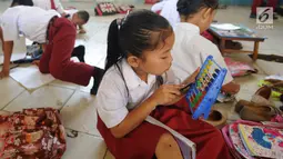 Seorang murid kelas II melakukan kegiatan belajar di lantai kelas SDN Kertajaya 2, Rumpin, Bogor, Senin (3/9). Tidak tersedianya meja dan kursi di tiga ruang kelas menyebabkan mereka belajar di lantai selama lebih dari 3 tahun. (Merdeka.com/Arie Basuki)