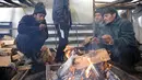 Para imigran menghangatkan diri dekat api unggun dalam tenda darurat di Kamp Lipa, luar Bihac, Bosnia, Jumat (8/1/2021). Cuaca bersalju dan musim dingin telah membawa lebih banyak penderitaan bagi ratusan imigran yang terjebak selama berhari-hari di kamp tersebut. (AP Photo/Kemal Softic)