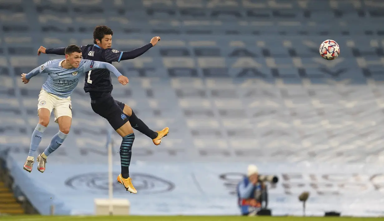 Gelandang Manchester City, Phil Foden berebut bola dengan bek Marseille, Hiroki Sakai pada pertandingan lanjutan Grup C Liga Champions di stadion Etihad di Manchester di London, Kamis (10/12/2020). Hasil ini membuat City lolos ke babak 16 besar bersama Porto. (AP Photo/Jon Super)