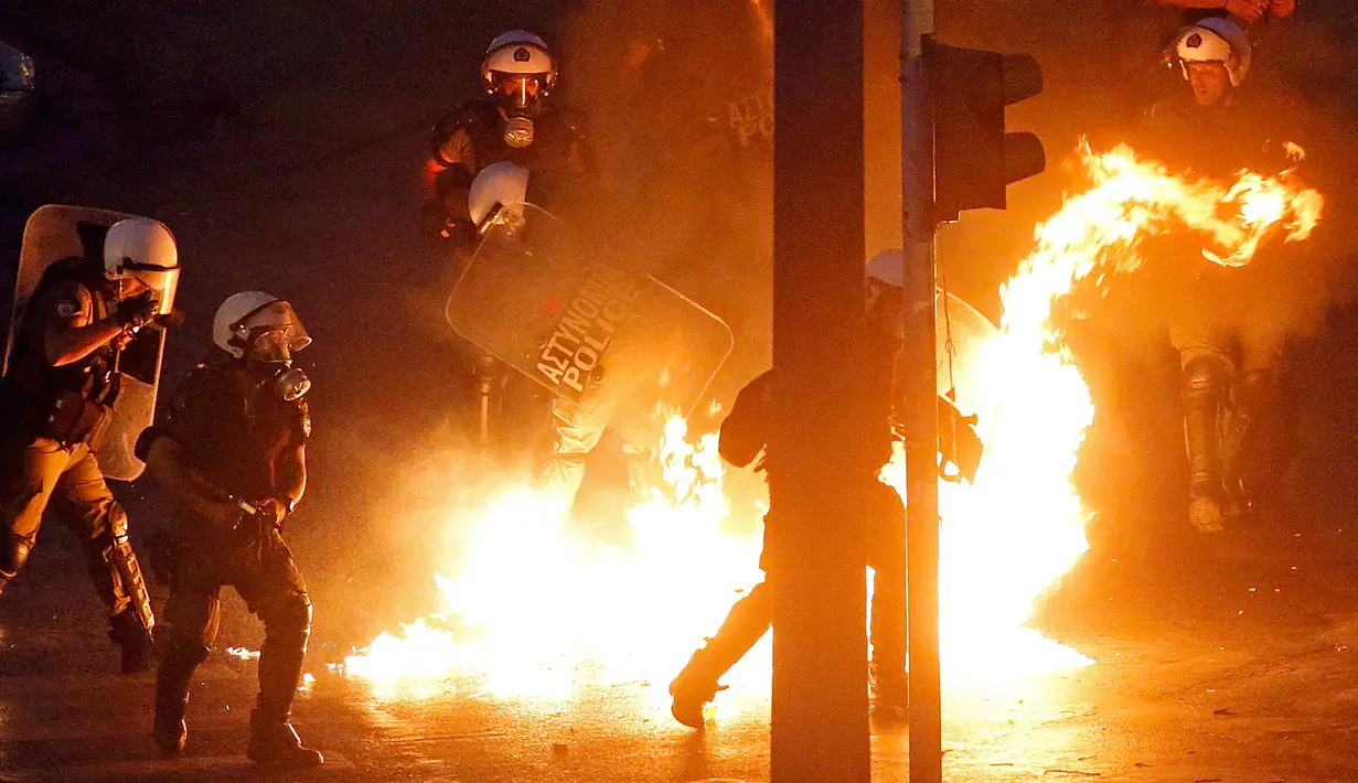 Polisi menghindari api bom molotov yang dilempar pengunjuk rasa anti-bailout di Athena, Yunani, Rabu (15/7/2015). Unjuk rasa ini dilakukan menjelang pemungutan suara kesepakatan bailout. (REUTERS/Jean-Paul Pelissier)