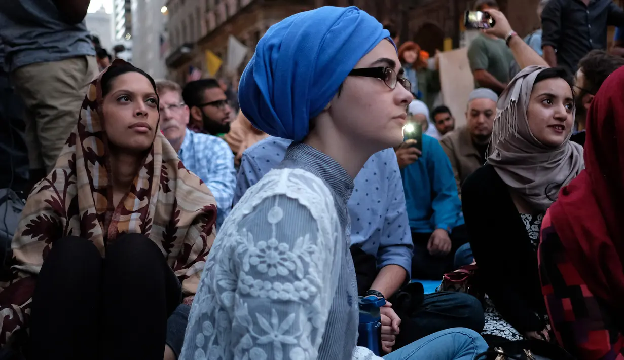 Umat muslim dan aktivis pendukung menunggu waktu berbuka puasa di dekat Trump Tower, New York, Kamis (1/6). Ratusan muslim berdemo memprotes retorika dan kebijakan Donald Trump yang xenophobia, seperti larangan perayaan Ramadan di AS. (Jewel SAMAD/AFP)