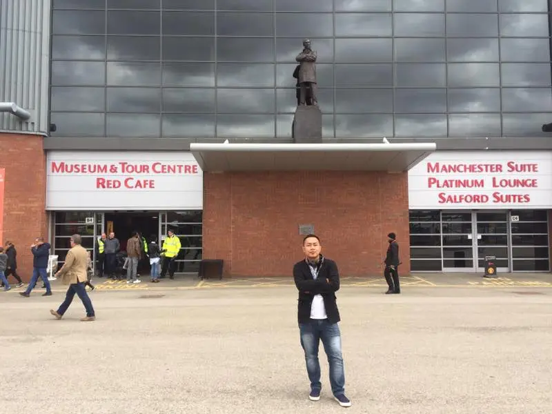 Joko Setyo Pramuji, kontributor Bola.com saat berada di stadion Old Trafford, menyempatkan diri berfoto di depan patung Sir Alex Ferguson, Kamis (13/04/2017). (Bola.com/Joko Setyo Pramuji)