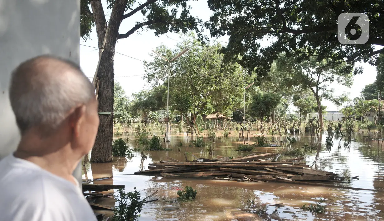 Seorang penjaga makam, Ismail (78) melihat kondisi banjir yang merendam pemakaman di Pulo Nangka, Jakarta, Minggu (23/2/2020). Selain permukiman, banjir merendam ribuan makam di Pulo Nangka hingga ketinggian mencapai 70 cm. (merdeka.com/Iqbal S. Nugroho)