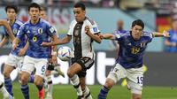 Pemain Timnas Jerman, Jamal Musiala (tengah) berebut bola dengan pemain Timnas Jepang, Hiroki Sakai dalam laga matchday pertama Grup E Piala Dunia 2022 di Khalifa International Stadium, Doha, Qatar, Rabu (23/11/2022) malam WIB. (AP/Ebrahim Noroozi)