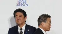 Presiden Korea Selatan (kiri) berjabat tangan dengan Perdana Menteri Jepang Shinzo Abe (kanan) di KTT G-20 tahun 2019 (AFP/Kim Kyung-Hoon)