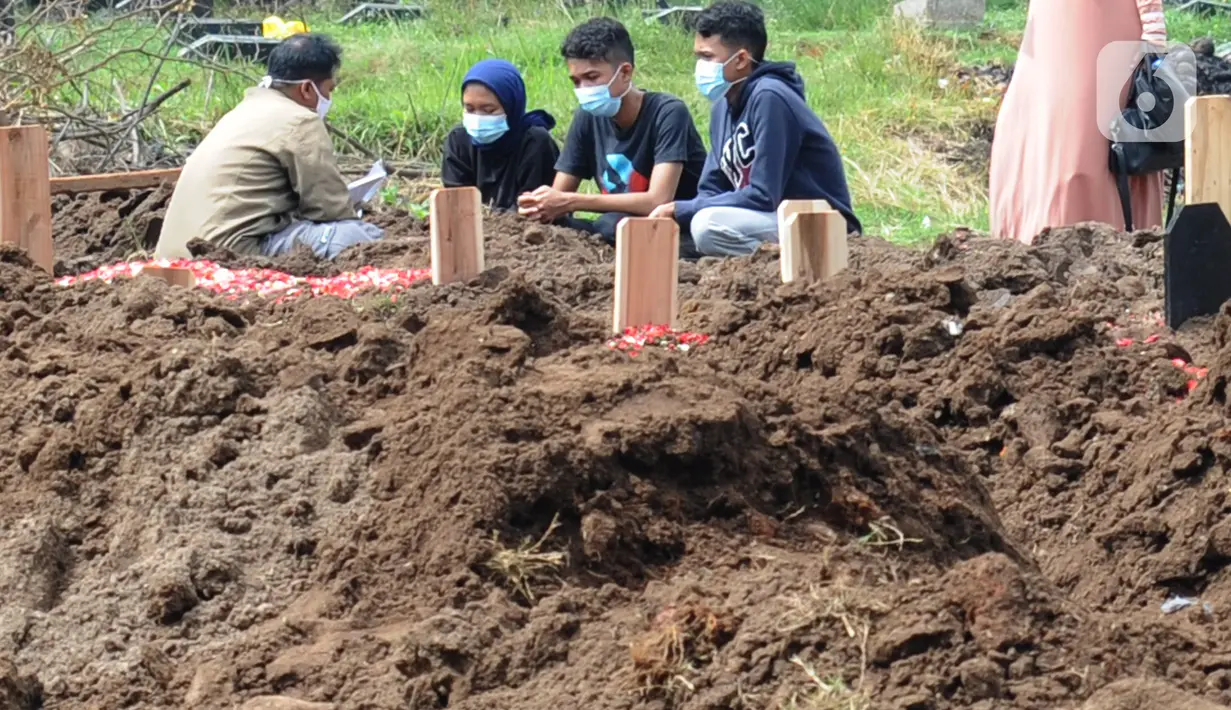 Sebuah keluarga berdoa di salah satu makam khusus Covid-19 di TPU Tegal Alur, Jakarta, Kamis (17/12/2020). Hingga hari ini, intensitas pemakamanan korban covid-19 di DKI masih tinggi dengan rata-rata yang dimakamkan mencapai 30 hingga 38 jenazah per hari. (merdeka.com/Arie basuki)
