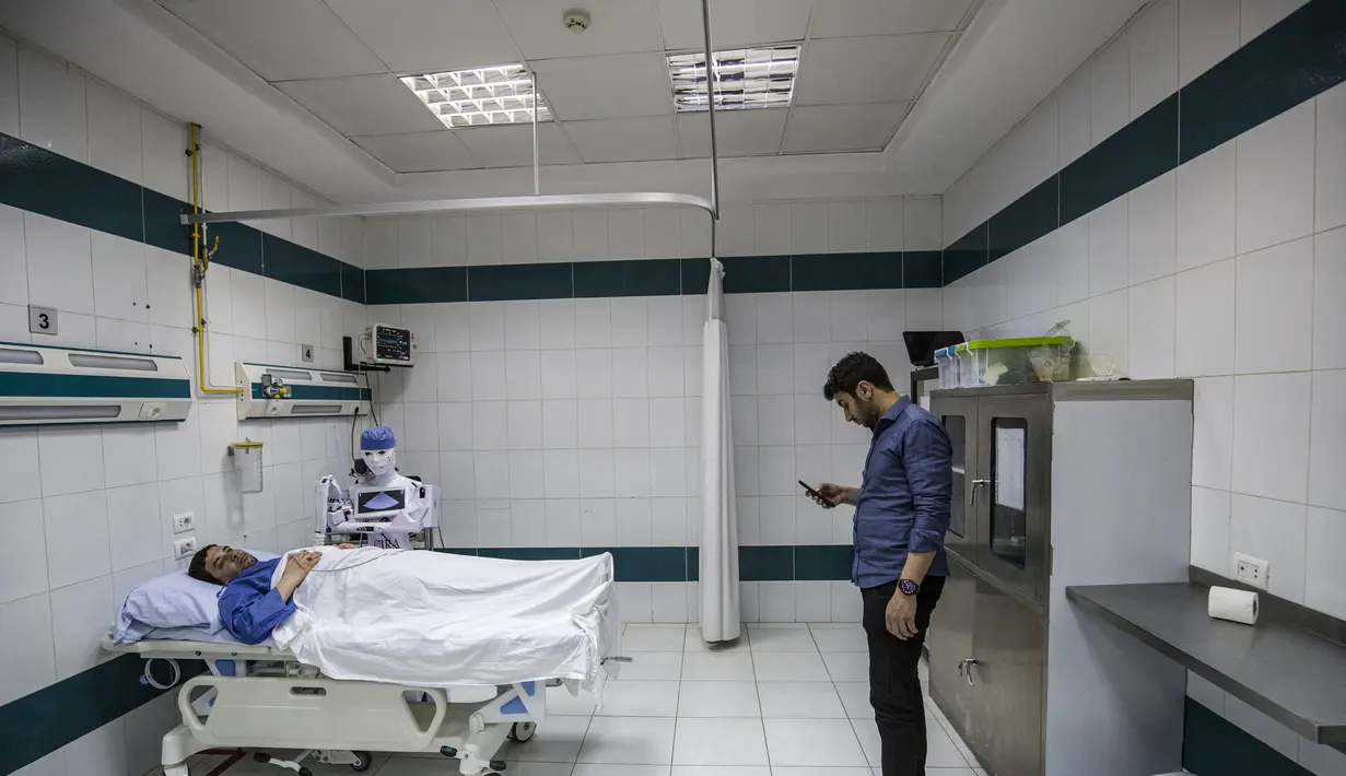 Mahmoud El Komy, seorang insinyur mekatronika, menguji prototipe robot CIRA-03 kendali jarak jauh yang didanai sendiri untuk membantu dokter dalam menjalankan tes pada pasien yang dicurigai COVID-19 di rumah sakit swasta di kota Tanta, Mesir pada 20 Maret 2021. (Khaled DESOUKI/AFP)