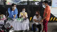 Seorang wanita memegang tangan suaminya saat bersiap menerima suntikan vaksin COVID-19 Sinovac di pusat vaksinasi drive-thru di Manila, Selasa (22/6/2021). Presiden Filipina Rodrigo Duterte mengancam akan memenjarakan orang-orang yang menolak untuk divaksinasi virus corona. (AP Photo/Aaron Favila)