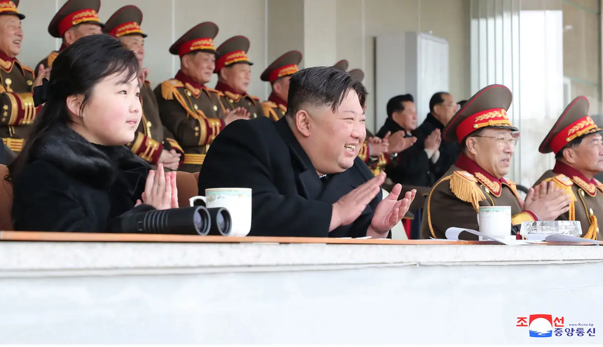 Pemimpin Korea Utara Kim Jong Un dan putrinya Kim Ju-ae bertepuk tangan saat menyaksikan pertandingan sepak bola antara staf Kabinet dan Kementerian Pertahanan Nasional, di Korea Utara pada 17 Februari 2023. Kim Jong Un mengajak putrinya dalam rangka merayakan ulang tahun kakeknya Kim Jong Il menandai penampilan pertama gadis itu yang tidak secara terbuka terkait dengan nuklir. (AFP/KCNA Via KNS)