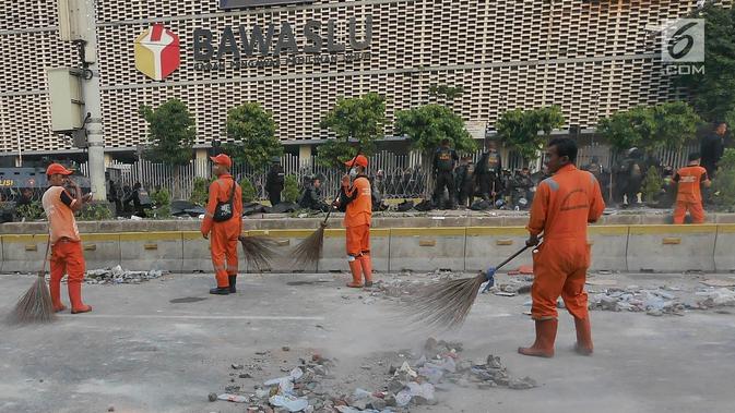 Petugas Penanganan Prasarana dan Sarana Umum (PPSU) atau Pasukan Oranye membersihkan sisa puing-puing pasca kerusuhan di MH. Thamrin. (Liputan6.com/Herman Zakharia)