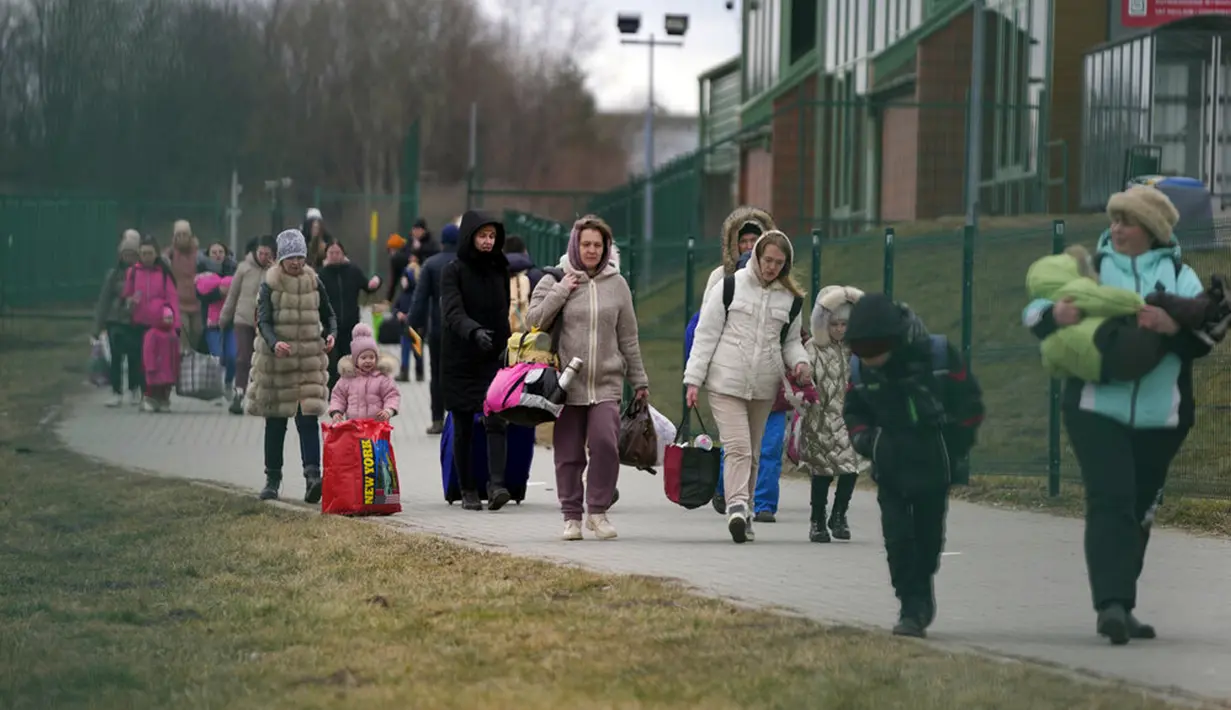 Warga yang melarikan diri dari Ukraina membawa barang-barang mereka saat berjalan di perbatasan di Medyka, Polandia, 8 Maret 2022. PBB mengatakan, serangan gencar Rusia telah memaksa lebih dari 2 juta orang meninggalkan Ukraina. (AP Photo/Markus Schreiber)
