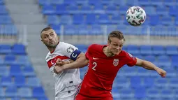 Penyerang Turki, Burak Yilmaz berebut bola dengan bek Norwegia, Stian Gregersen pada lanjutan Kualifikasi Piala Dunia 2022 zona Eropa Grup G di stadion La Rosaleda di Malaga, Spanyol, Minggu (28/3/2021). Turki menang telak atas Norwegia 3-0. (AP Photo/Fermin Rodriguez)