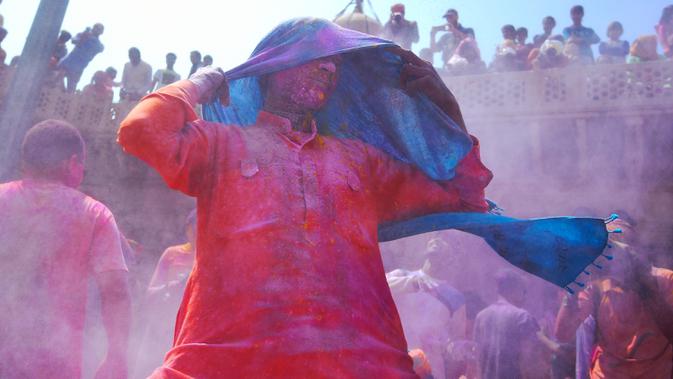 Umat Hindu menari saat merayakan Holi, festival warna musim semi, di sebuah kuil di desa Nandgaon, Uttar Pradesh, 5 Maret 2020. Ribuan orang India menyambut musim semi pada Kamis (5/3) dengan merayakan Festival Holi yang identik dengan aksi saling melemparkan bubuk warna warni. (Money SHARMA/AFP)