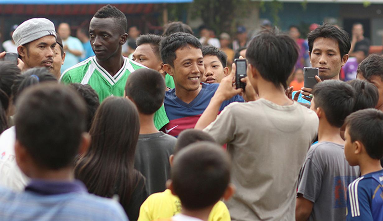 Warga setempat  berebut mengajak foto bersama Makan Konate pemain Persib. (Bola.com/Peksi Cahyo)