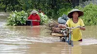 Dua pencari kayu dan pakan ternak melintasi banjir di Desa Wonoasri, Tempurejo, Jember, Jawa Timur.(Antara)