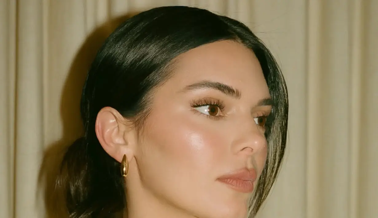 Wajahnya dipulas makeup warm, dengan blush on coral di pipi serta lipstik kecoklatan di bibir. Riasan mata pun dibuat soft.  [@kendalljenner:]