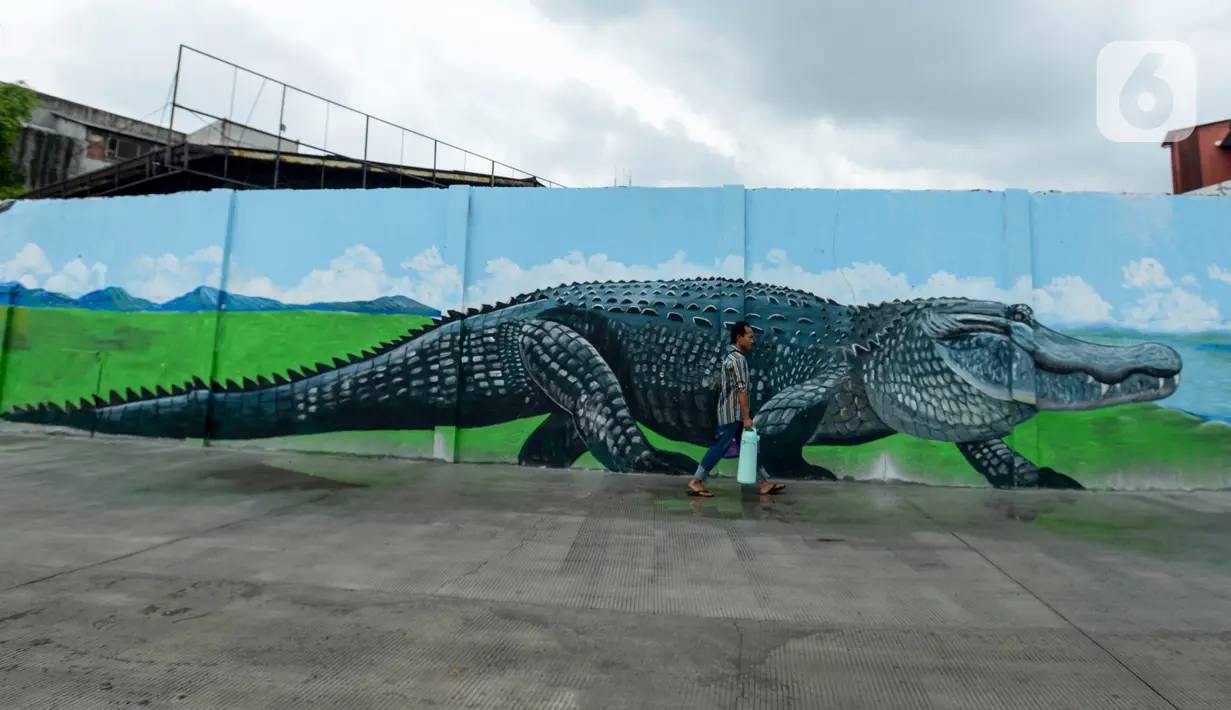 Warga melintasi kreasi mural di sepanjang dinding bantaran Kali Opak, Jakarta Utara, Kamis (6/2/2020). Tembok bangunan saat ini tak hanya menjadi pembatas semata tapi dimanfaatkan untuk menyampaikan pesan-pesan dan harapan dalam bentuk goresan atau tulisan. (merdeka.com/Imam Buhori)