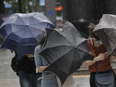 Orang-orang berjuang dengan payung mereka melawan angin kencang dan hujan di pusat kota Seoul, Korea Selatan, Kamisn (3/9/2020). Topan Maysak kuat melanda wilayah semenanjung Korea. (AP Photo/Lee Jin-man)